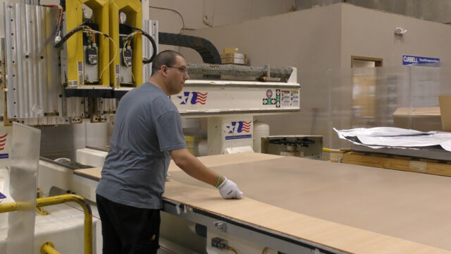Curbell employee cuts a large sheet of plastic
