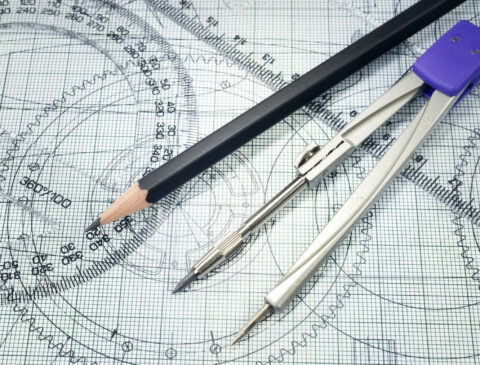 Pencil, rulers, and compass laying on top of grid paper